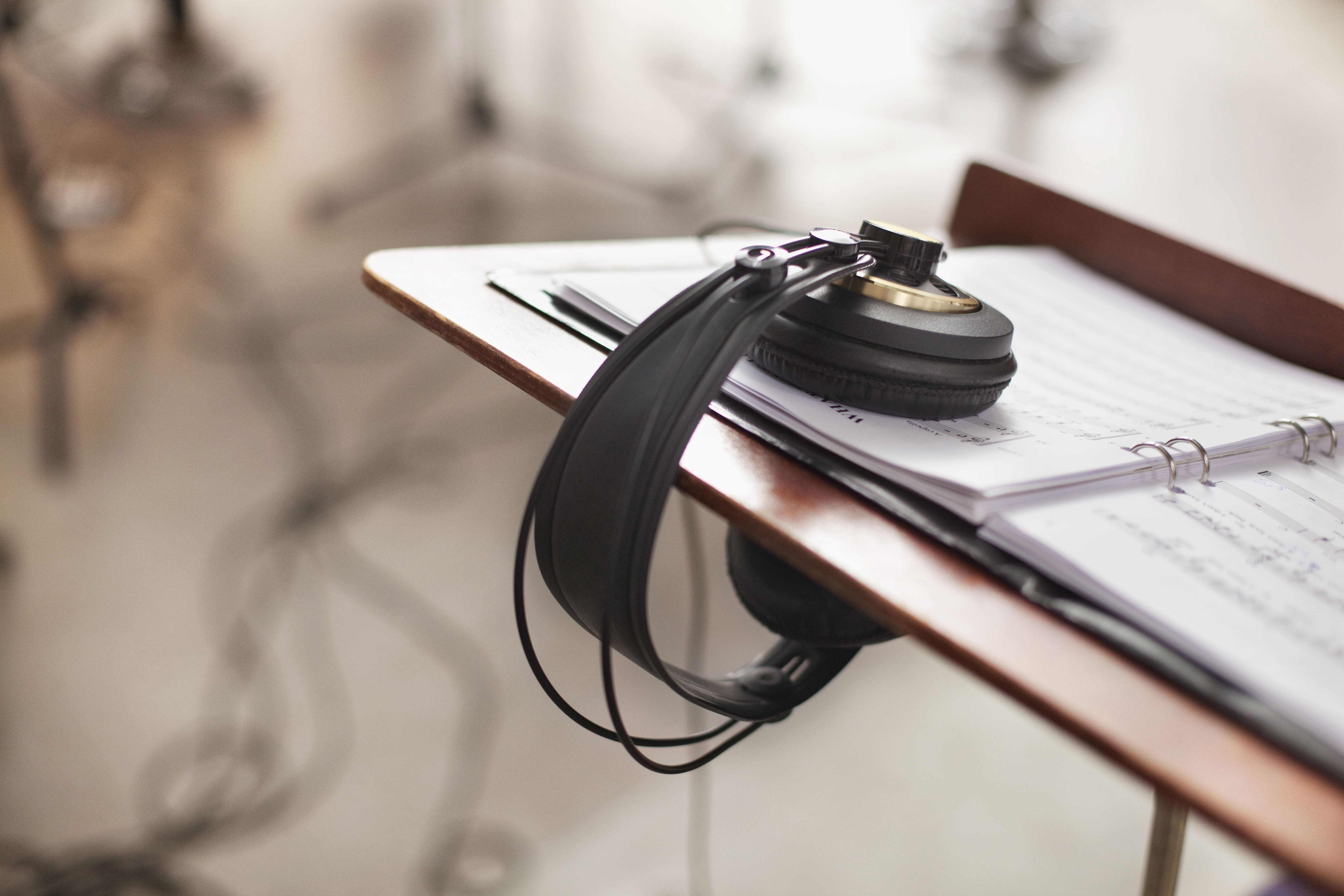 Primer plano de micrófonos, auriculares y mesa de mezclas como equipamiento esencial para grabación de obras clásicas en un estudio profesional.