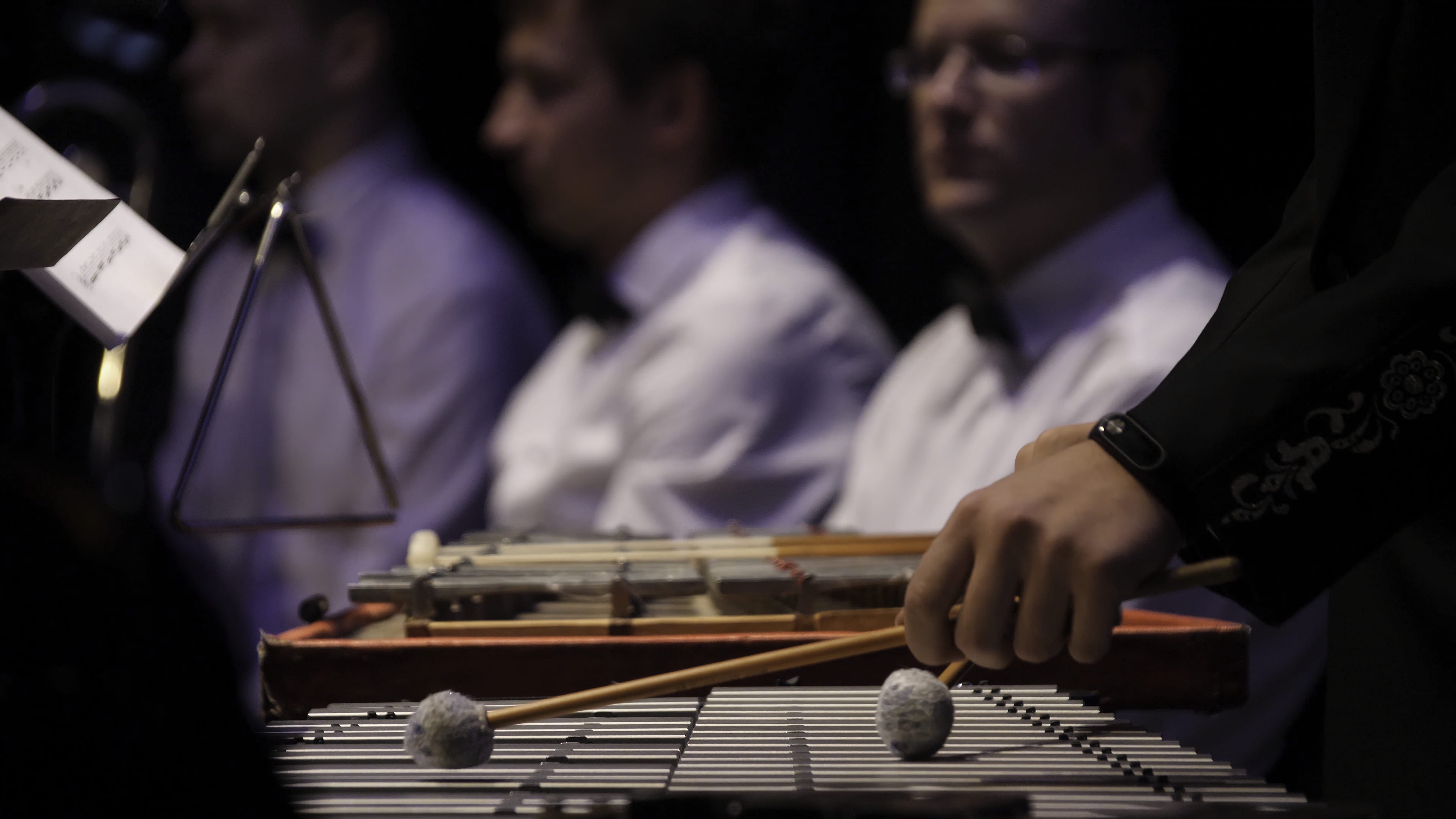 Ingeniero de sonido corrigiendo errores comunes al grabar música clásica, músicos revisando partituras y equipo en estudio de grabación.